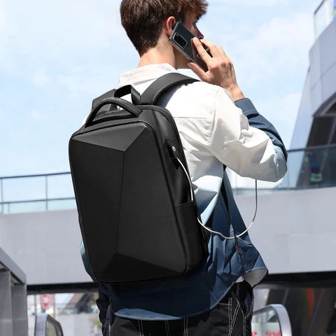 Homme utilisant le sac-a-dos-antivol-nomad-shield, dos noir extensible avec sangle pour valise et port USB, dans un aéroport.