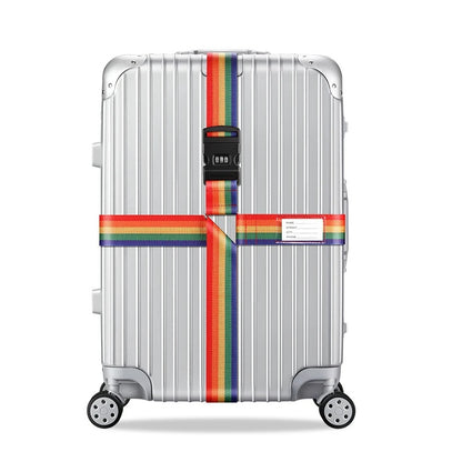 Sangle pour valise croisée antivol à code fixée sur une valise rigide argent, utilisée en situation réelle dans un aéroport, avec poignée télescopique tirée par un voyageur. arc en ciel