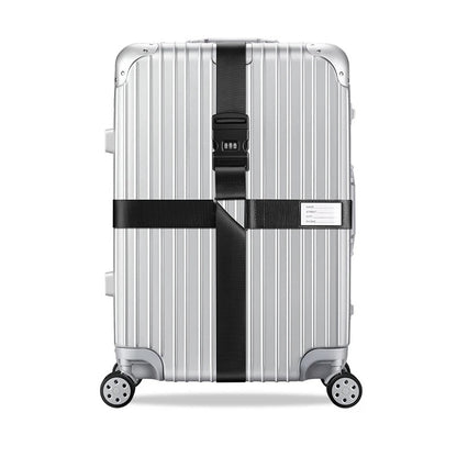 Sangle pour valise croisée antivol à code fixée sur une valise rigide argent, utilisée en situation réelle dans un aéroport, avec poignée télescopique tirée par un voyageur. noir